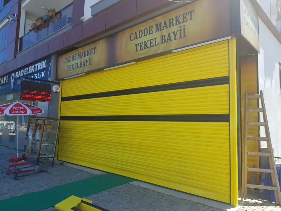 Market cephesinde siyah şeritli sarı otomatik kepenk